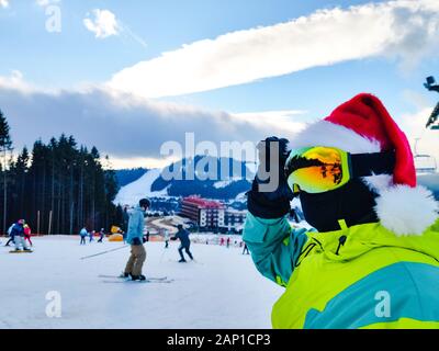 Homme heureux en tenue de ski avec le père Noël Noël rouge hat au winter mountains hill Banque D'Images