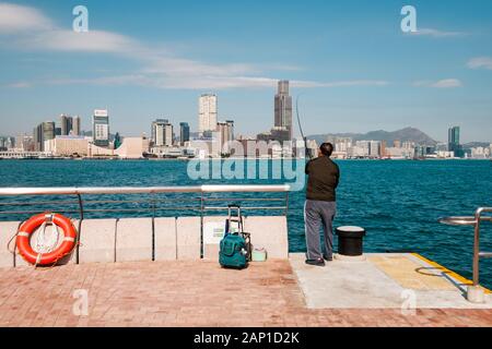 Fisher man avec la canne à pêche sur la côte, avec des toits de Hong Kong, Kowloon Banque D'Images