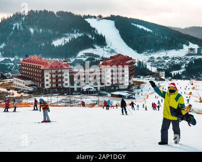 Homme avec snowboard à red christmas hat walking up par neigé hill Banque D'Images