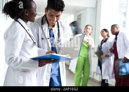 Portrait de médecins, de race mixte. Une fille noire, avec un mec mexicain, en blouse blanche, avec les stéthoscopes, tient des documents médicaux, une consultation, une Banque D'Images