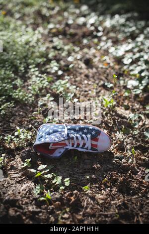 Une chaîne hi-top chaussures en toile avec un motif du drapeau américain abandonné dans les sous-bois Banque D'Images