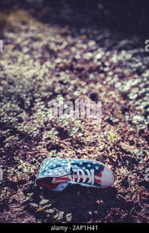 Une chaîne hi-top chaussures en toile avec un motif du drapeau américain abandonné dans les sous-bois Banque D'Images