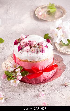 Joyeuses Pâques décoration pour carte de vœux. Gâteau de pâques avec glaçage blanc, Guimauve, Rose et fleurs sèches de couleur rose du papier craft sur fond gris. Banque D'Images