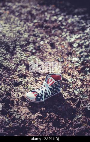 Une chaîne hi-top chaussures en toile avec un motif du drapeau américain abandonné dans les sous-bois Banque D'Images