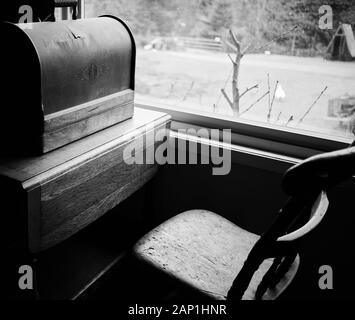 boîte à coudre en bois de bois de bois de bois de bois poussiéreux ancien et ancienne chaise à côté d'une fenêtre. Noir et blanc. Banque D'Images