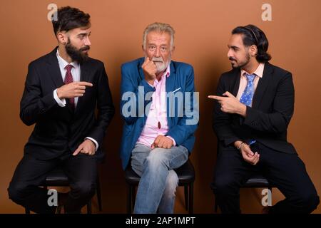 Trois hommes barbus multi ethnic ensemble contre fond brun Banque D'Images