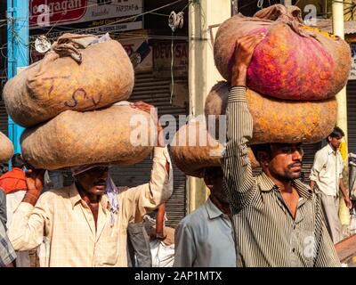 Les travailleurs portent des sacs remplis de fleurs sur leur tête sur le marché de gros de fleurs Banque D'Images