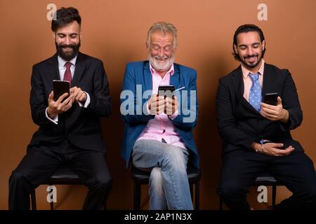 Trois hommes barbus multi ethnic ensemble contre fond brun Banque D'Images