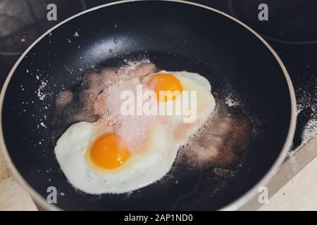 Photographie d'appétissants œufs brouillés d'un oeuf de poule dans une casserole avec l'huile de tournesol d'ébullition Banque D'Images