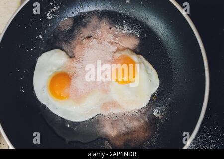 Photographie d'appétissants œufs brouillés d'un oeuf de poule dans une casserole avec l'huile de tournesol d'ébullition Banque D'Images