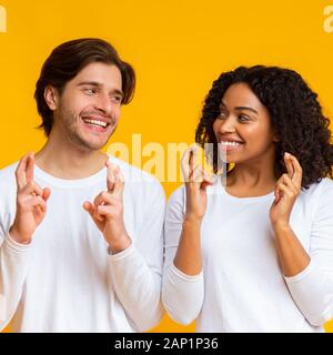 Multiraciale romantique couple crossing fingers, rendant ainsi souhaiter Banque D'Images