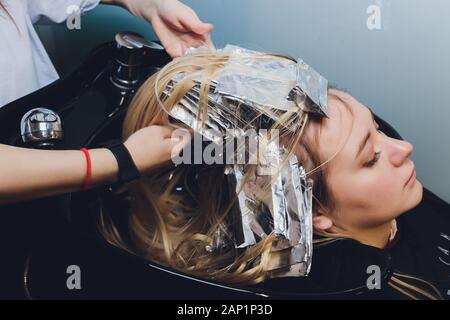 Libre de coiffure mains séparant les brins de cheveux de belle jeune femme avec une feuille d'aluminium avant de changer la couleur des cheveux Banque D'Images