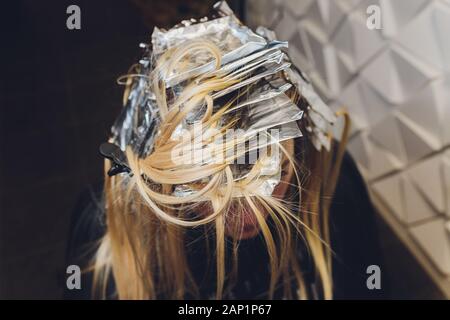 Libre de coiffure mains séparant les brins de cheveux de belle jeune femme avec une feuille d'aluminium avant de changer la couleur des cheveux Banque D'Images