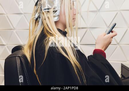 Libre de coiffure mains séparant les brins de cheveux de belle jeune femme avec une feuille d'aluminium avant de changer la couleur des cheveux Banque D'Images