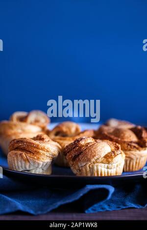 Pâtisseries modernes à la mode.cruffins Frais cuits (croissant et mouffin) avec cannelle et sucre brun sur fond bleu avec espace pour le texte Banque D'Images