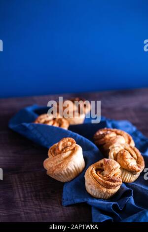 Pâtisseries modernes tendance.cruffins Frais (croissant et mouffin) avec cannelle et sucre brun sur fond en bois et espace de copie de serviette en tissu Banque D'Images