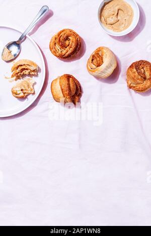 Croûtes modernes tendance à pâtisseries (croissant et mouffin) avec cannelle, sucre et beurre de noix de cajou végétalien sur fond rose pastel avec espace de copie Banque D'Images