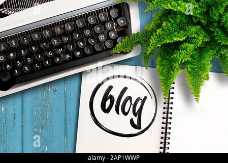 Concept de blogging, vue du dessus de la vieille machine à écrire, plante en pot et bloc-notes avec Word blog sur table en bois Banque D'Images