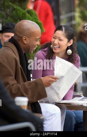 African American man et woman lire article at outdoor cafe Banque D'Images