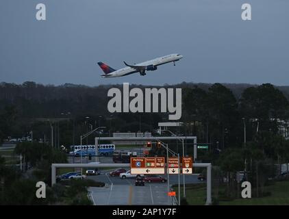 Un avion de Delta Airlines prend son décollage à l'aéroport international d'Orlando alors que les autobus prennent les passagers. Banque D'Images