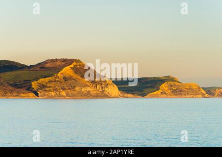 Lyme Regis, dans le Dorset, UK. 20 janvier 2020. Météo britannique. La Côte Jurassique falaises de Cap d'Or (à gauche) et Thorncombe Beacon (droite) glow orange en fin d'après-midi soleil peu avant le coucher du soleil vu de Lyme Regis dans le Dorset à la fin d'une froide journée ensoleillée. Crédit photo : Graham Hunt/Alamy Live News Banque D'Images