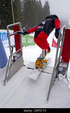 Coupe du monde de snowboard 2020 Rogla, en Slovénie. Un concurrent au moment de quitter le portail de démarrage et l'accélération commence en bas de la piste. Banque D'Images