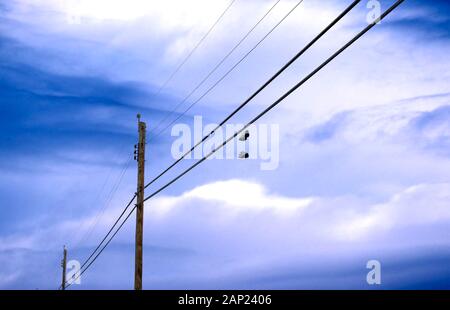 Une paire de chaussures sur les lignes électriques qui pendent sous un ciel nuageux ciel bleu, une métaphore pour désertion et l'abandon Banque D'Images