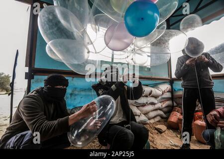 Bureij, Territoires palestiniens. 20 Jan, 2020. Palestiniens masqués fixer des dispositifs incendiaires et matériaux inflammables aux préservatifs remplis de gaz réfrigérant avant d'être libéré pour être propulsé par le vent dans le territoire israélien, près de la frontière Israel-Gaza. Credit : Mohammed Talatene/dpa/Alamy Live News Banque D'Images