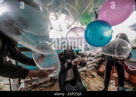 Bureij, Territoires palestiniens. 20 Jan, 2020. Palestiniens masqués fixer des dispositifs incendiaires et matériaux inflammables aux préservatifs remplis de gaz réfrigérant avant d'être libéré pour être propulsé par le vent dans le territoire israélien, près de la frontière Israel-Gaza. Credit : Mohammed Talatene/dpa/Alamy Live News Banque D'Images