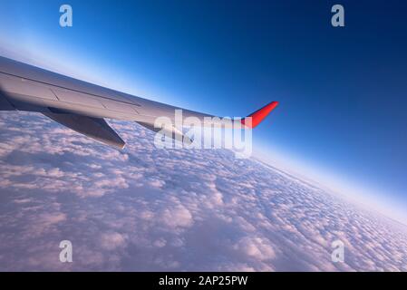 Ciel à travers la fenêtre de l'avion, lever du soleil au-dessus des nuages Banque D'Images