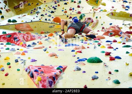 Homme mur d'escalade dans la salle de sport de bloc. Détails sur les jambes et l'équipement Banque D'Images