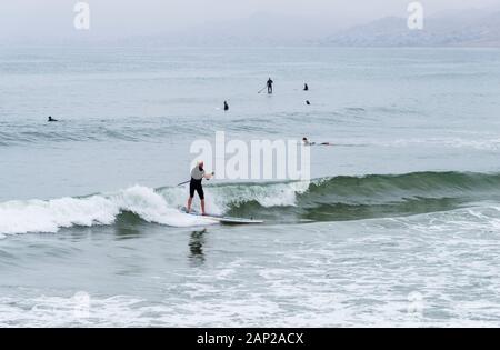 Les surfeurs capturent des vagues viviviviantes du Pacifique à Morro Rock Beach lors d'une matinée estivale surmoulée le long de la côte californienne. Banque D'Images