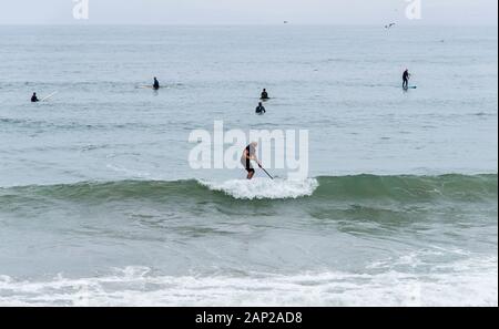 Les surfeurs capturent des vagues viviviviantes du Pacifique à Morro Rock Beach lors d'une matinée estivale surmoulée le long de la côte californienne. Banque D'Images