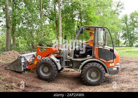 Travailleur de la construction conduit un petit chargeur à roues sur le site de construction Banque D'Images