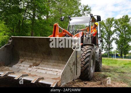Travailleur de la construction conduit un petit chargeur à roues sur le site de construction Banque D'Images