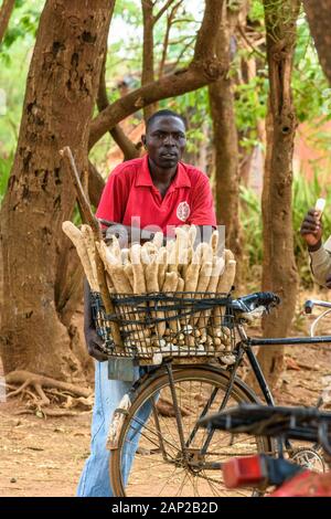 Un homme malawien vend de la casava à sa bicyclette dans un village malawien Banque D'Images