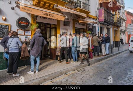 Foule en dehors du bar à tapas espagnol animé en hiver, Séville, Andalousie, Espagne du Sud. Banque D'Images