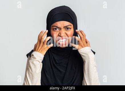 Dame musulmane en colère en hijab et grimaçant émotionnellement gesturing in rage Banque D'Images