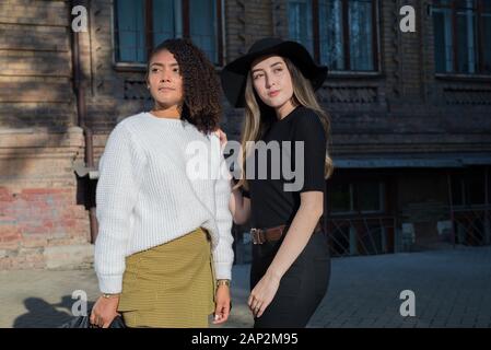 Une paire de belles filles mexicaines debout contre la toile d'un vieux bâtiment universitaire. Deux soeurs. Les jeunes filles. Prise de vue de la mode. G Banque D'Images