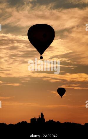 Deux montgolfières se profilent au coucher du soleil au-dessus d'un paysage de l'Iowa pendant le National Balloon Classic. Banque D'Images