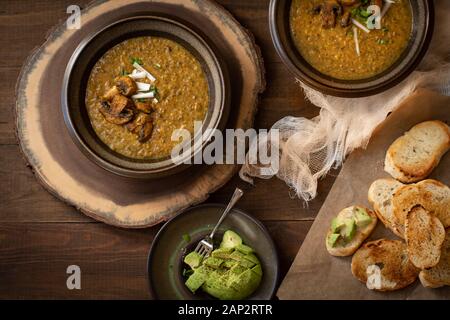 Vegan crème de champignon sur table en bois avec du pain grillé et de l'avocat Banque D'Images