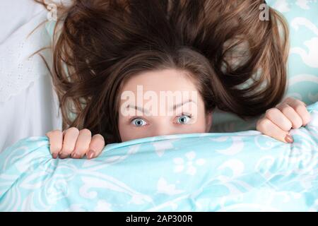 Fille incroyable avec des yeux ouverts à la recherche de sous les couvertures Banque D'Images