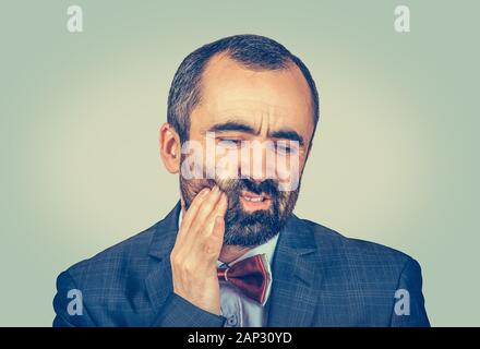 Closeup portrait homme mûr avec dents sensibles problème de la couronne sur le point de pleurer de douleur de toucher l'extérieur de la bouche à part isolé sur bac vert clair Banque D'Images