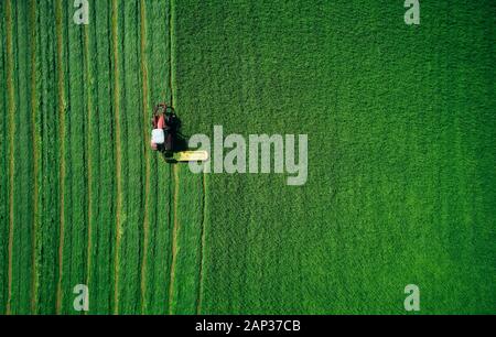 Au-dessus du tracteur en mouvement Rouge sur vert lumineux et le labourage du champ des semis en journée ensoleillée Banque D'Images