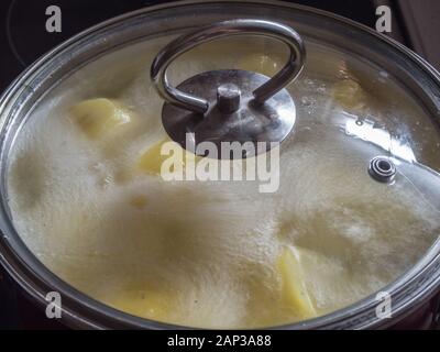 Nettoyer les pommes de terre dans une casserole d'eau bouillante Banque D'Images