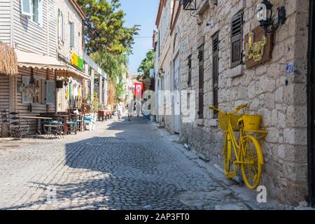 Cesme, Turquie - 6 septembre 2019 : les gens marcher dans une rue pavée et yellow bicycle. De nombreux touristes visitent la ville. Banque D'Images