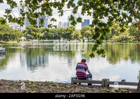 Bangkok, Thaïlande - 27 septembre 2018 : l'homme est assis au bord du lac dans le Parc Lumphini. Le parc se trouve dans le centre de la ville. Banque D'Images