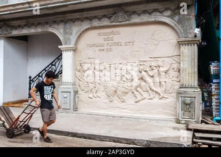 Bangkok, Thaïlande - 25 septembre 2012 : un porteur passe devant une peinture murale représentant l'Yodpiman flower market. Le marché a été ouvert depuis 1961. Banque D'Images