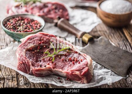 Bifteck de faux-filet de boeuf avec sel poivre et romarin sur table en bois Banque D'Images