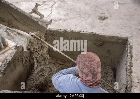 La dernière pelle travailleur ciment humide couler le béton mix de camion benne en métal en chute pour un autre processus. Banque D'Images